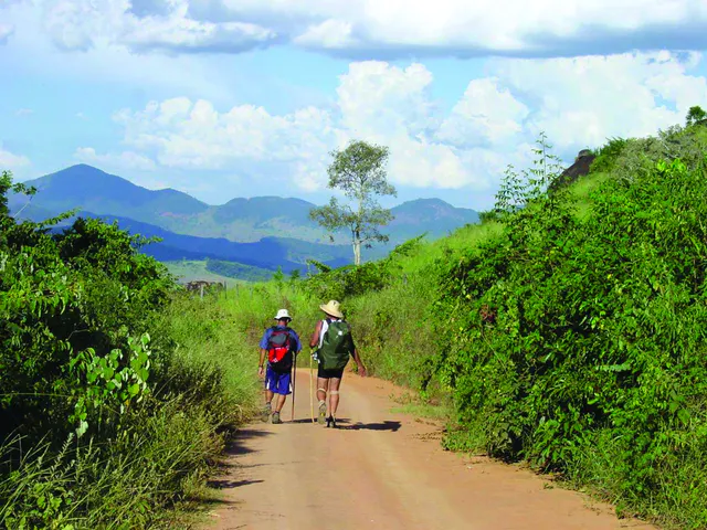 Caminhantes em uma estrada rural cercada por montanhas