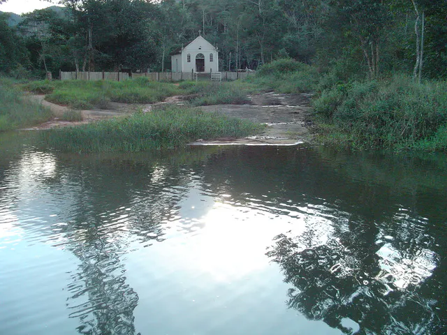 Lago cercado por vegetação e uma pequena construção