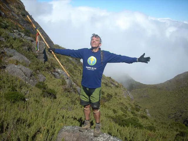 Caminhante com os braços abertos diante das montanhas