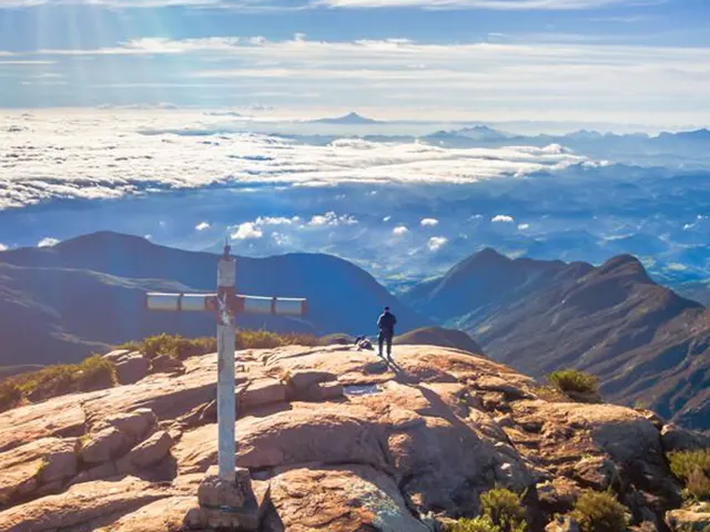 Cruz no alto de uma montanha com vista para os vales